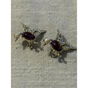 A pair of vintage silver-tone bird brooches with purple stones and rhinestones.